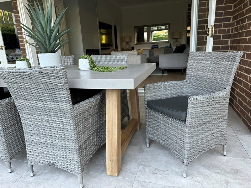 Corner of grey wicker chairs surrounding grey dining table outdoors